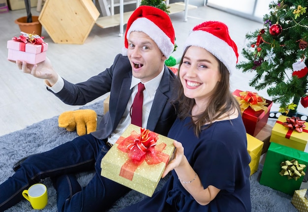 Bonne année 2022, concept, Happy couple holding échangeant des cadeaux et Offrir un cadeau à la fête de Noël et du Nouvel An Fond d'arbre de Noël Après avoir terminé le travail commercial