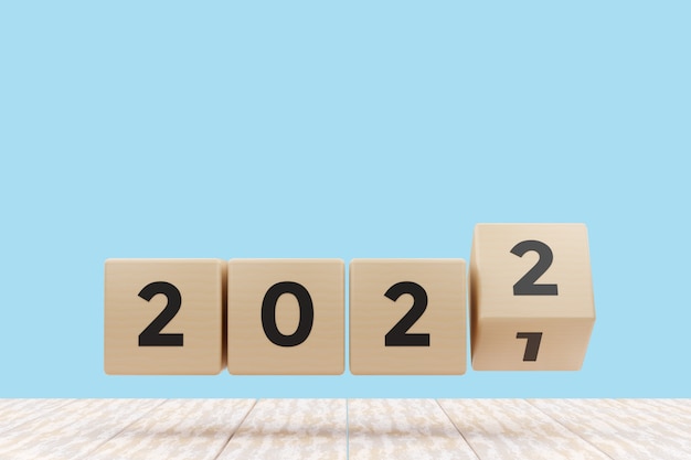 Bonne année 2022. Cube en bois avec numéro 2021 changement en 2022 sur fond bleu de table blanche. Rendu d'illustrations 3D.