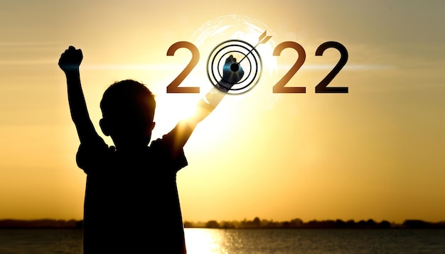 Bonne année 2022. Silhouette d'enfant sur la côte au coucher du soleil.