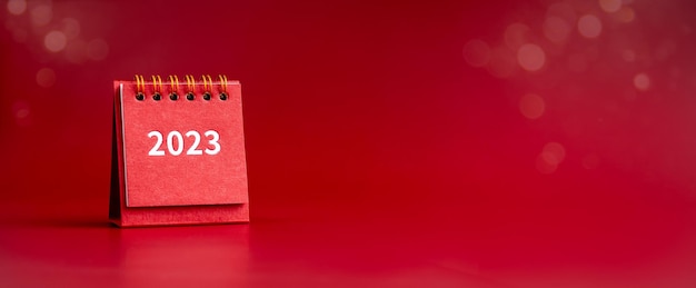 Bonne année 2023 bannière 2023 numéros année sur petite couverture de calendrier de bureau rouge isolé sur fond rouge avec espace de copie minimaliste Prêt à commencer de nouveaux objectifs