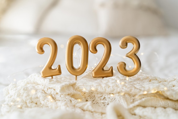 Bonne année 2023 Fond de Noël avec bougies 2023 et pull en tricot blanc Célébration des vacances de Noël Concept du Nouvel An