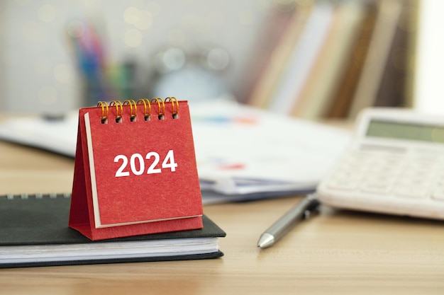 Photo bonne année 2024 calendrier rouge sur le bureau mettre en place des objectifs d'affaires et de planification budgétaire pour la nouvelle année