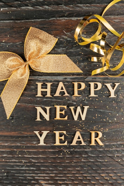 Bonne année texte en bois décoré d'un arc doré et d'une serpentine sur fond noir en bois carte de vœux festive pour les fêtes du Nouvel An