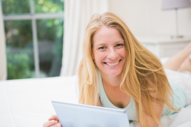 Bonne blonde à l&#39;aide de tablet pc sur le lit