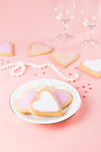 Photo bonne carte de voeux pour la saint-valentin avec des biscuits au cœur, des verres à vin et du vin sur un fond rose pastel