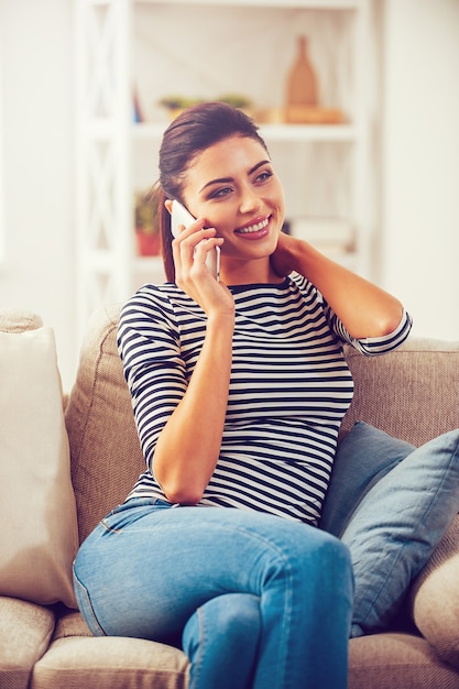 Bonne conversation avec un ami. Belle jeune femme parlant au téléphone portable et souriant