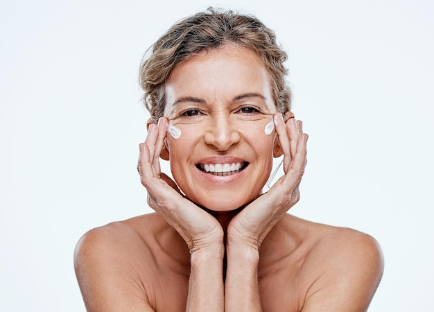 Une bonne crème hydratante fera le plus gros du travail à votre place Photo d'une femme mûre posant avec une crème hydratante sur le visage