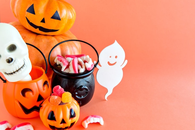 Bonne décoration d'Halloween. Citrouille, chaudron, crâne et bonbons gommeux sur fond orange.