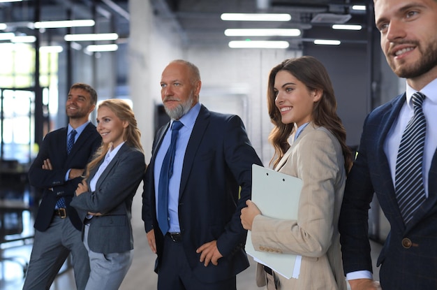 Bonne équipe commerciale souriante debout dans une rangée au bureau.