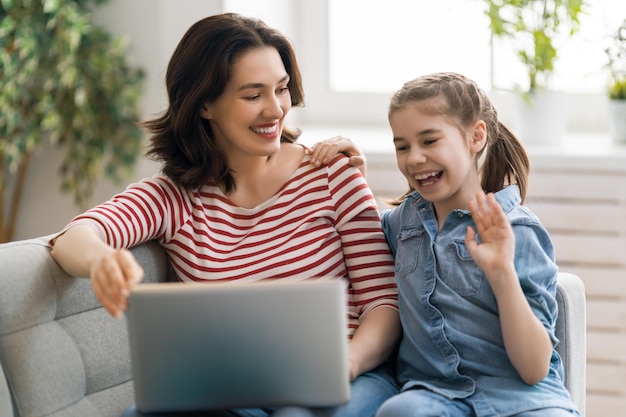 Bonne famille aimante. Jeune fille mère et fille à l'aide d'un ordinateur portable. Une maman amusante et un enfant adorable s'amusent à rester à la maison.