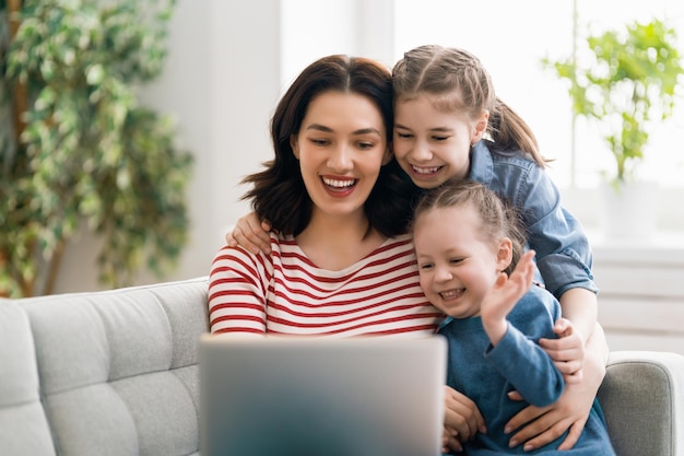 Bonne famille aimante. Jeunes filles mères et filles utilisant un ordinateur portable. Maman drôle et enfants adorables s'amusent à rester à la maison.