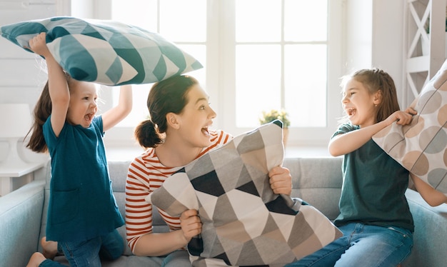 Bonne famille aimante! La mère et ses enfants filles se battent contre les oreillers.