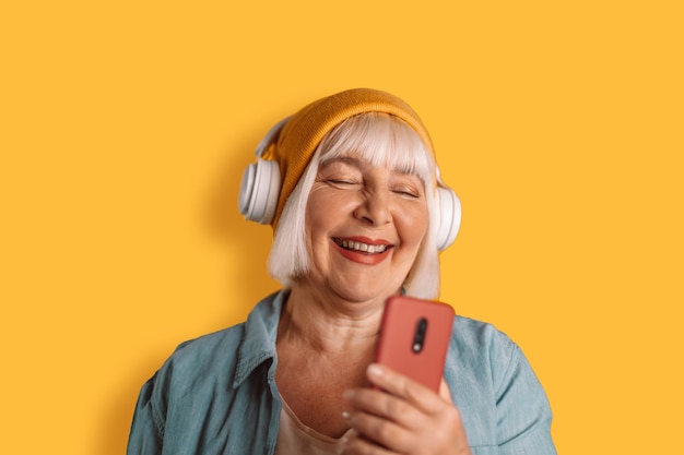 Bonne Femme Des Années 50 Casque écouter De La Musique Chanter Une Chanson Enregistrer La Voix Par Dictaphone De Téléphone Portable Sur Fond De Couleur Jaune Studio Portrait.