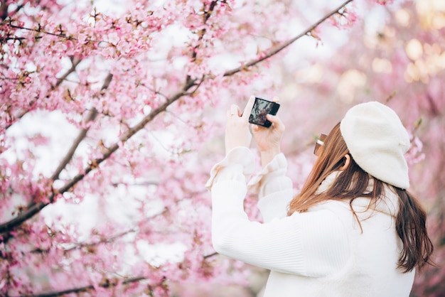 Bonne femme de voyage et prendre une photo de sakura cherry blossoms tree en vacances au printemps