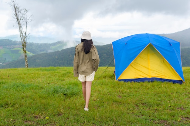 Bonne femme voyageuse appréciant et relaxant près de la tente de camp