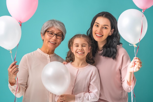 Bonne fête des femmes La fille de l'enfant félicite maman et grand-mère en leur donnant des ballons à air roses