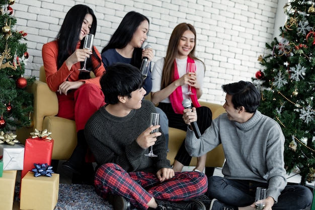 Bonne fête de jeunes asiatiques avec du vin et chantez une chanson à la maison pour célébrer le festival de Noël. Célébration du nouvel an à la maison. Joyeux Noël et joyeuses fêtes du gang teen thai.