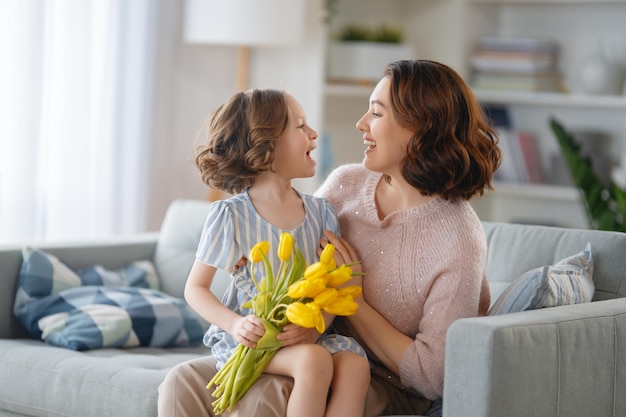 Bonne fête des mères Enfant fille félicitant maman et lui donnant des fleurs