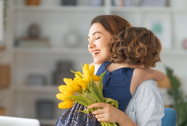 Bonne fête des mères Enfant fille félicitant maman et lui donnant des fleurs