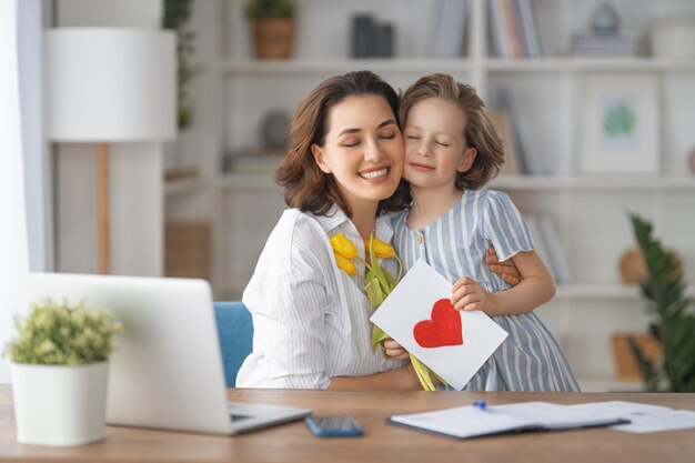 Bonne fête des mères Enfant fille félicitant maman et lui donnant des fleurs