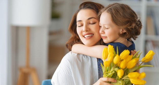 Bonne fête des mères Enfant fille félicitant maman et lui donnant des fleurs