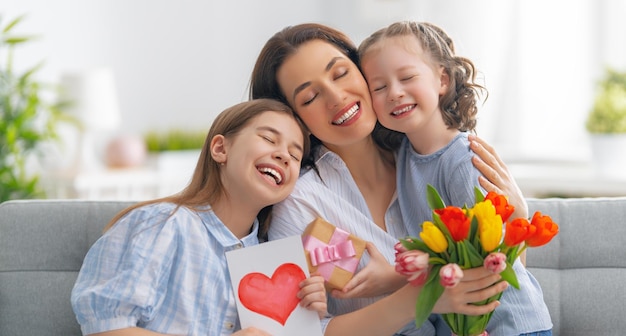 Bonne fête des mères Les enfants filles félicitent maman et lui donnent une carte postale et des fleurs