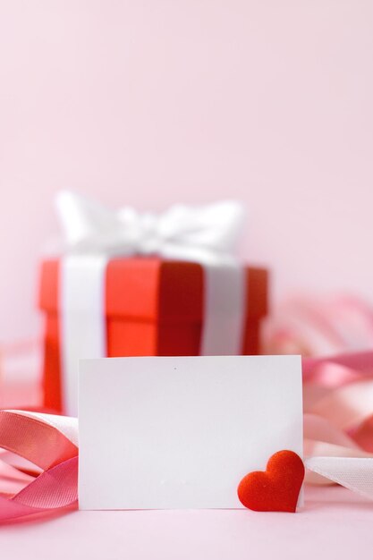 Bonne fête des mères ou fête des femmes Boîte rouge avec cadeau et carte de voeux blanche sur fond rose