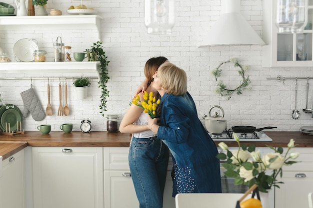 Bonne fête des mères La fille adulte félicite la mère âgée et lui donne des tulipes en fleurs