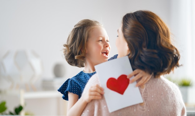 Bonne fête des mères La fille de l'enfant félicite maman et lui donne une carte postale Maman et fille souriante