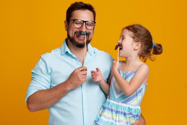 Bonne fête des pères drôle papa et fille avec moustache s'amuser sur fond jaune