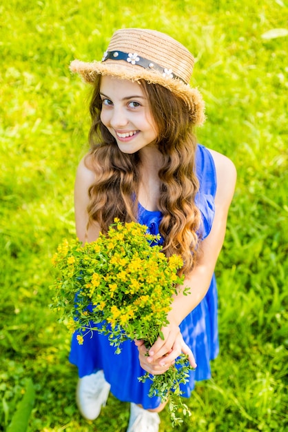 Bonne fille cheveux bouclés récoltant des herbes à fleurs dans des remèdes naturels sur le terrain