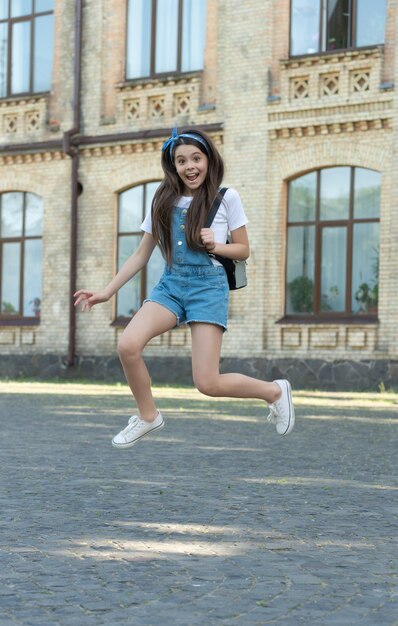 Bonne fille en denim avec sac à dos sautant en plein air