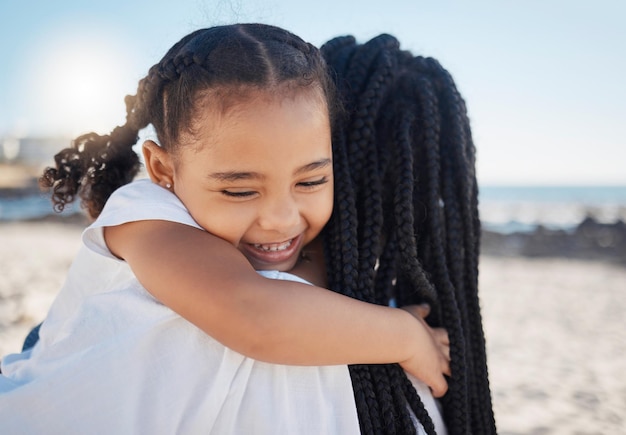 Bonne fille maman et câlin sur la plage pour les soins de l'amour ou le soutien pendant les vacances d'été ou se détendre au soleil Embrasser la mère et la fille à la mer ou à la nature pour le bonheur ensemble de la famille noire