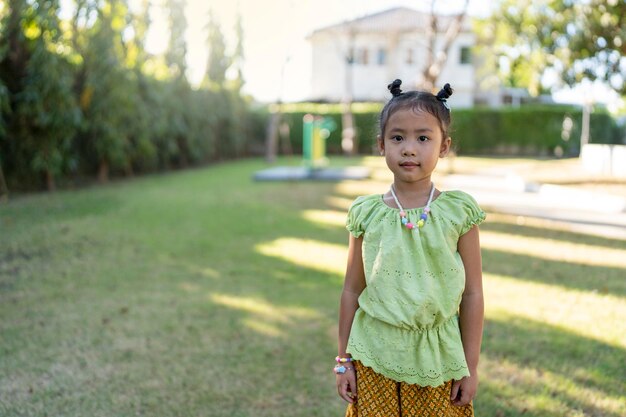 Bonne fille en robe traditionnelle thaïlandaise debout au parc.