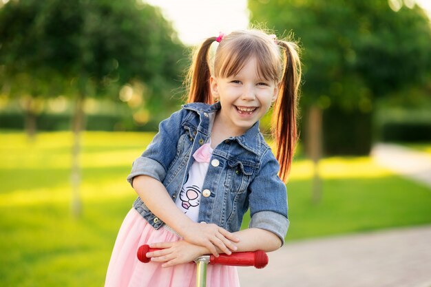 Bonne fille souriante de six ans dans le parc d'été