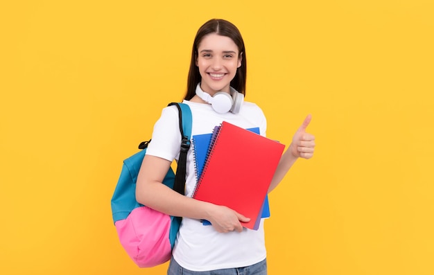 Bonne fille tenant un cahier sur fond jaune professeur privé avec des cahiers