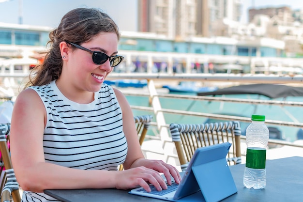 Bonne fille travaillant à distance dans la zone de la marina