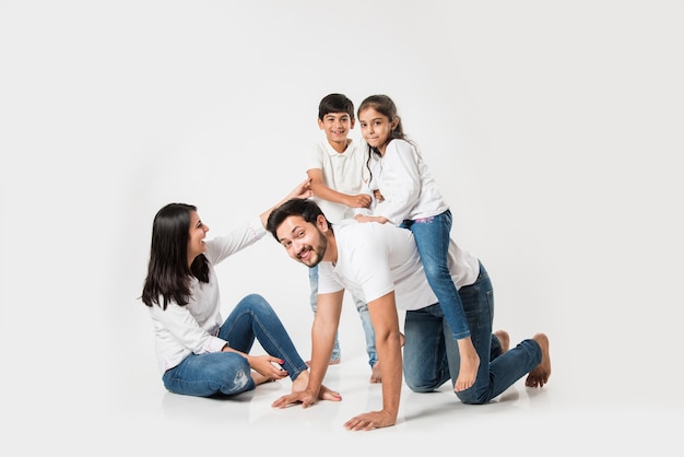 Bonne folle chevauchée sur le dos de père. Petite fille indienne assise sur le dos de papa pendant que mère et frère rient. mise au point sélective