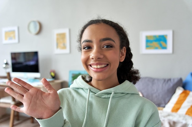 Photo bonne gen z adolescente agitant la main parlant à la caméra dans la chambre