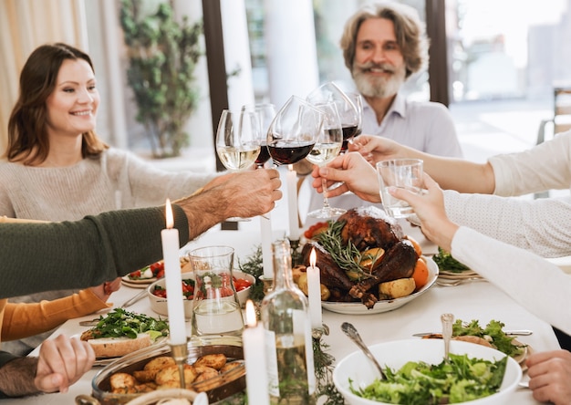 Bonne grande famille célébrant Noël ensemble à la maison, ayant un dîner de Noël traditionnel, grillant