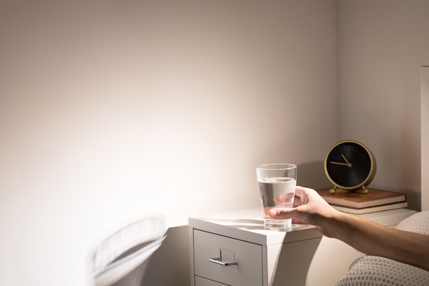 Bonne Habitude - Boire Un Verre D'eau Avant D'aller Dormir. Homme Au Lit Prenant Un Verre D'eau De La Table De Chevet Avant Le Coucher, Copiez L'espace.