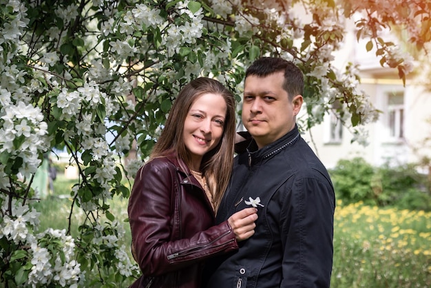 Bonne humeur concept portrait d'un jeune couple amoureux dans un parc fleuri de printemps étreignant et regardant la caméra