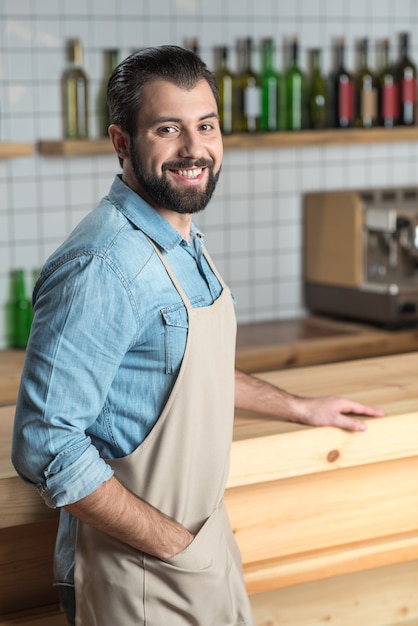 Bonne humeur. Enthousiaste jeune serveur responsable se sentant heureux d'être au travail debout et souriant amical