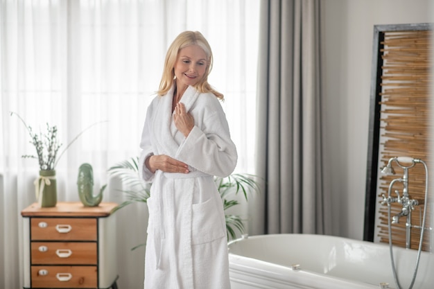 Bonne humeur. Femme blonde dans un peignoir blanc à la satisfaction