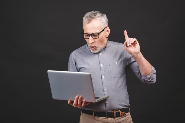 Bonne idée! Heureux homme âgé senior pointant vers le haut à l'espace de copie tout en tenant un ordinateur portable