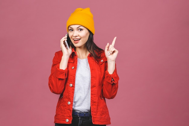 Bonne idée! Portrait d'une femme étonnée heureuse dans des vêtements lumineux, parler au téléphone isolé sur le mur rose.