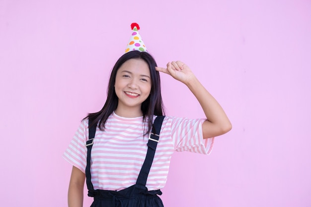 Bonne jeune fille porte un chapeau de fête sur fond rose, fille asiatique.