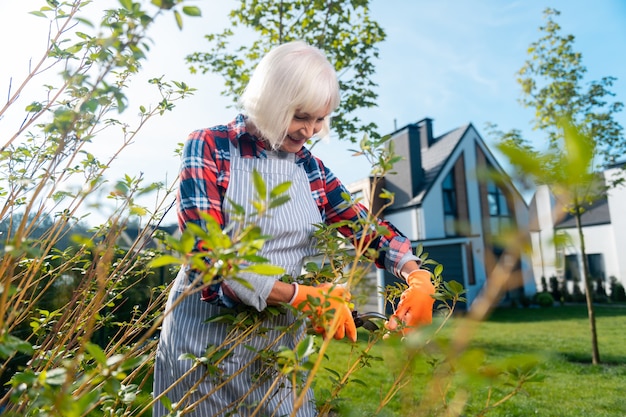 Bonne journée. Belle vieille femme passant une journée tout en travaillant dans le jardin