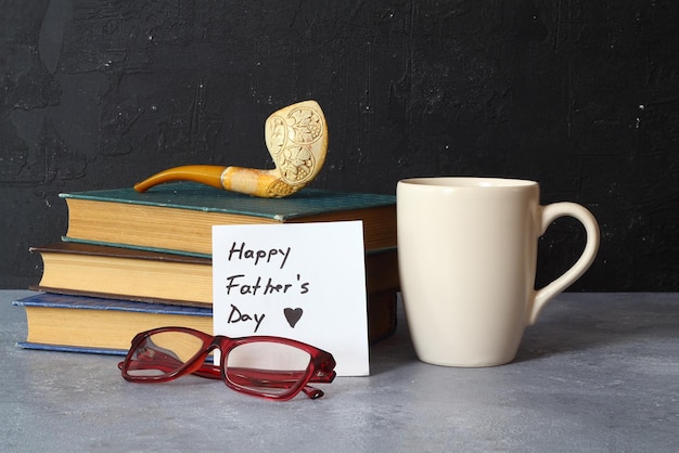 Bonne journée des pères concept avec des tasses de café, des verres et des livres sur fond en bois