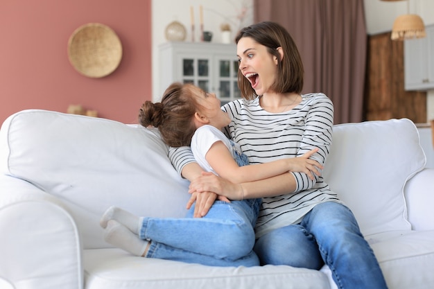 Bonne maman aimante embrassant sa petite fille, passez du temps ensemble à la maison.